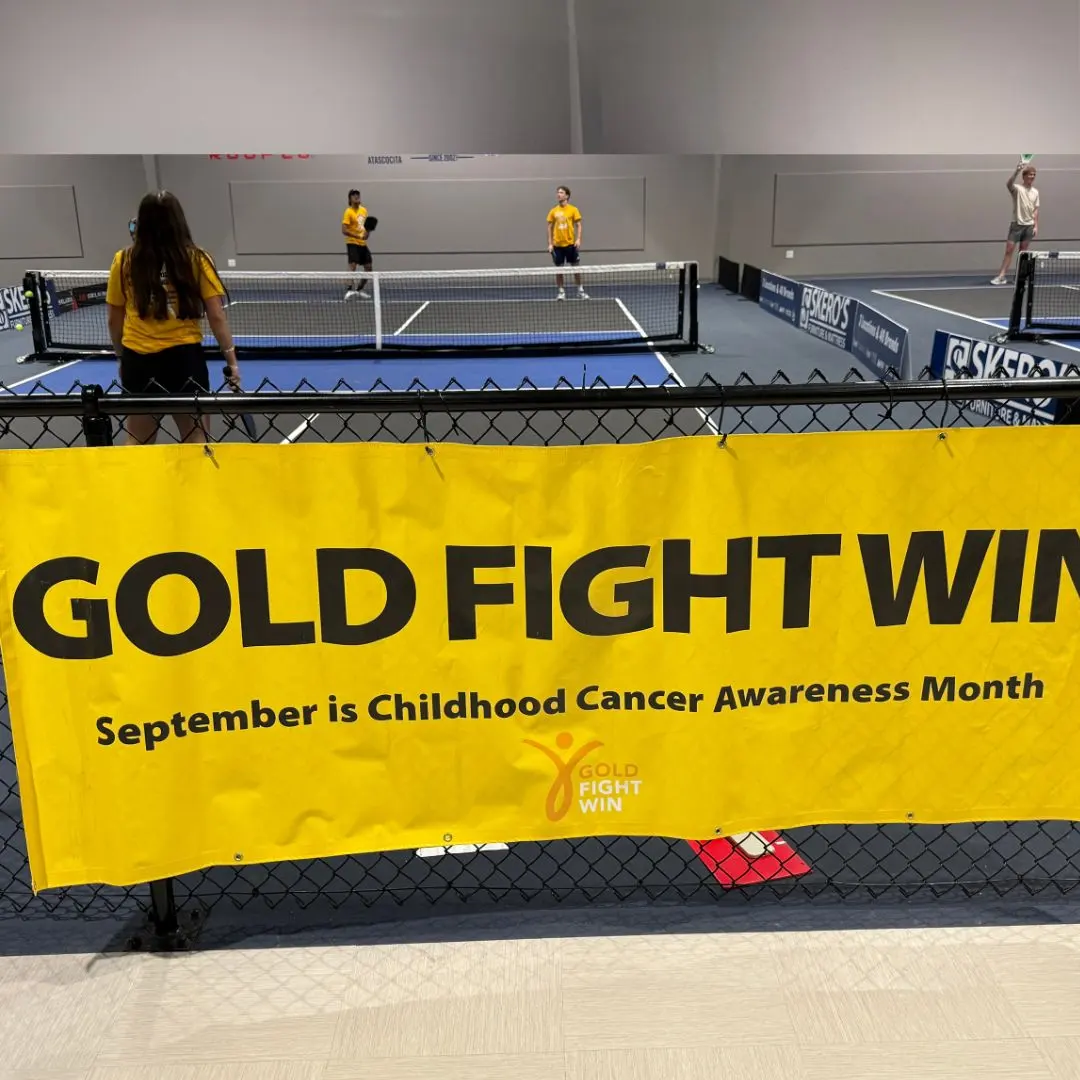Gold Fight Win banner for Childhood Cancer Awareness Month hanging over the courts